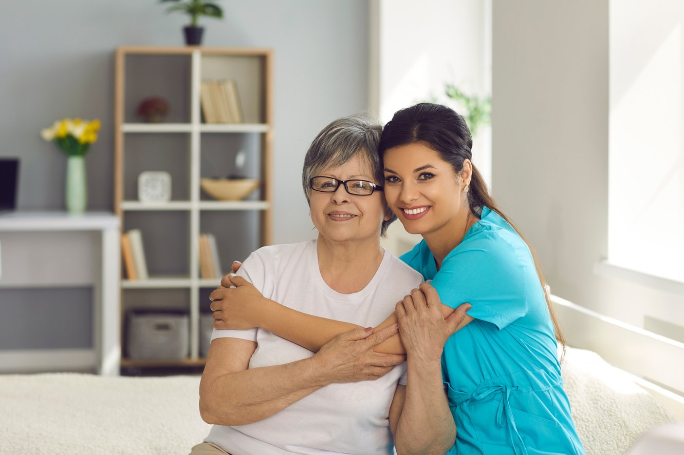 Happy Senior Woman Together with Her Home Care Nurse or Caregiver Smiling at Camera